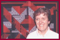 Picture of Dottie Gantt in front of art quilt "When One Door Closes ..."